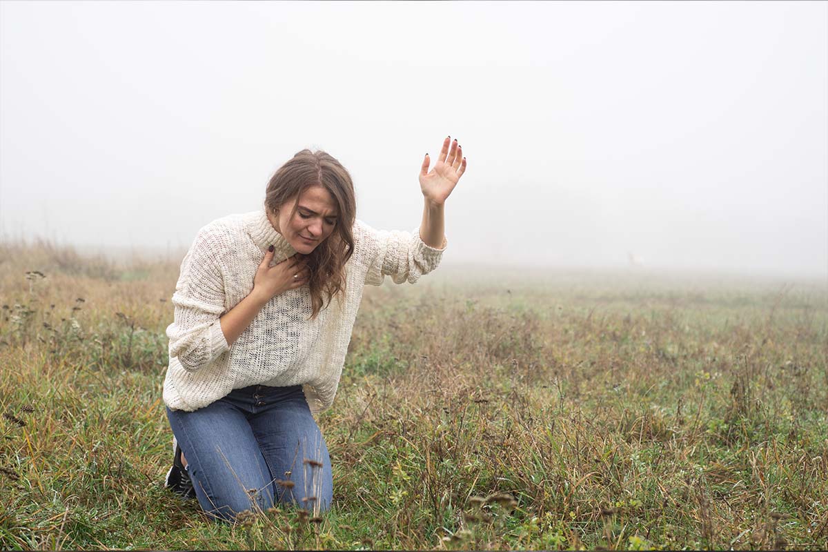 Girl closed her eyes on the knees, praying in a field during bea