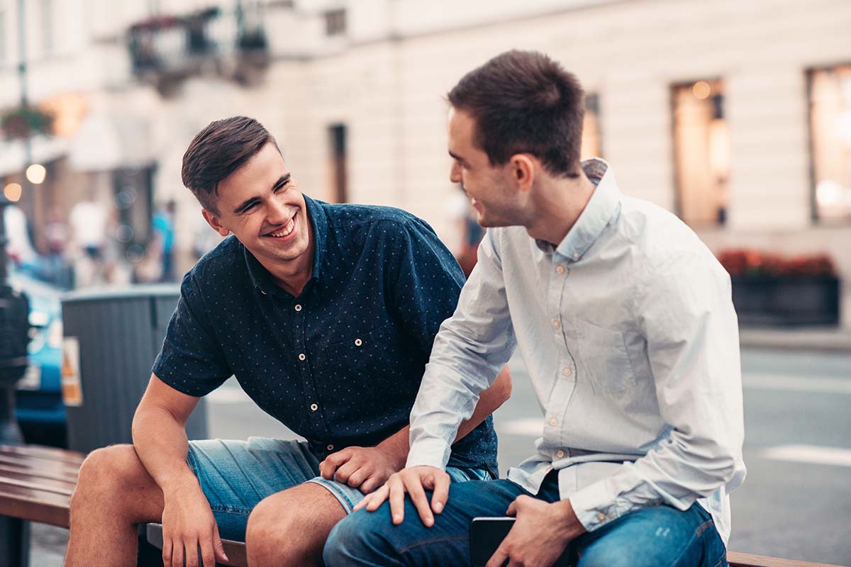 Friends talking together on a bench in the city