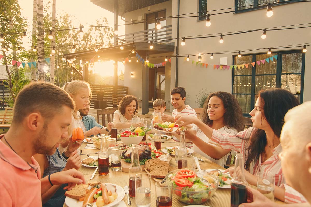 family sitting outside, eating and talking at large table