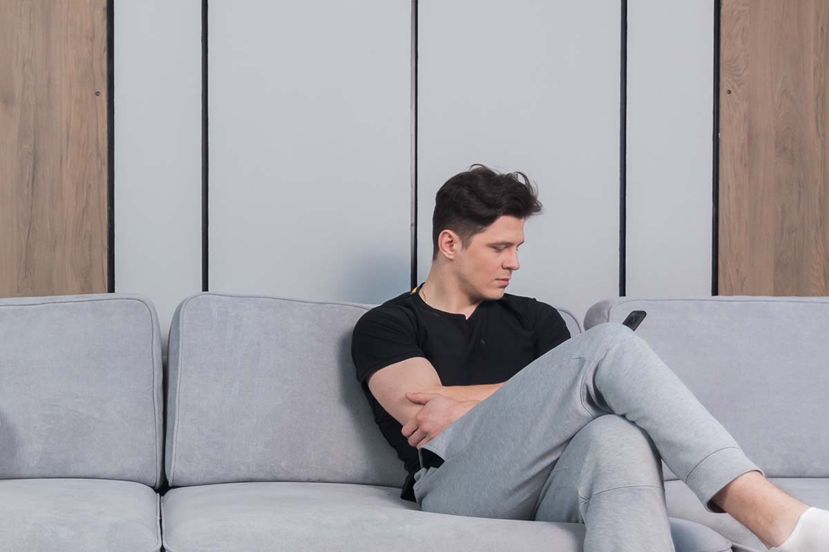 apathetic man on couch looking at phone