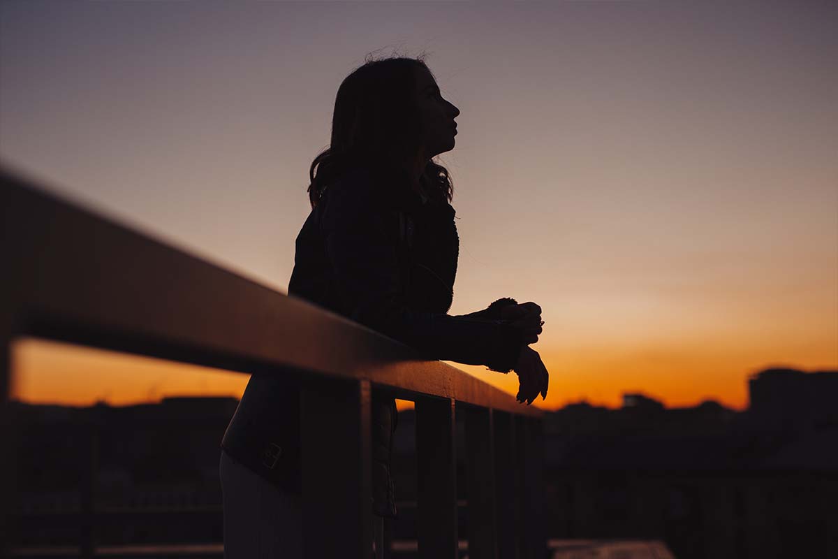 Girl resting on a fence at sunset thinking about authenticity in evangelism.